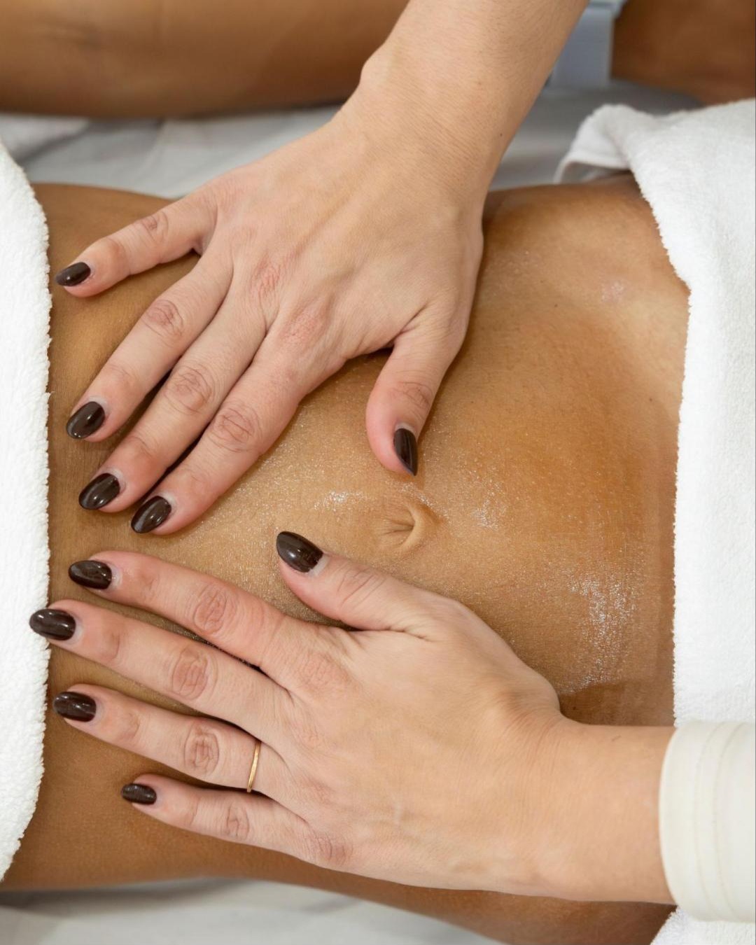 Mãos em massagem de drenagem linfática no abdómen